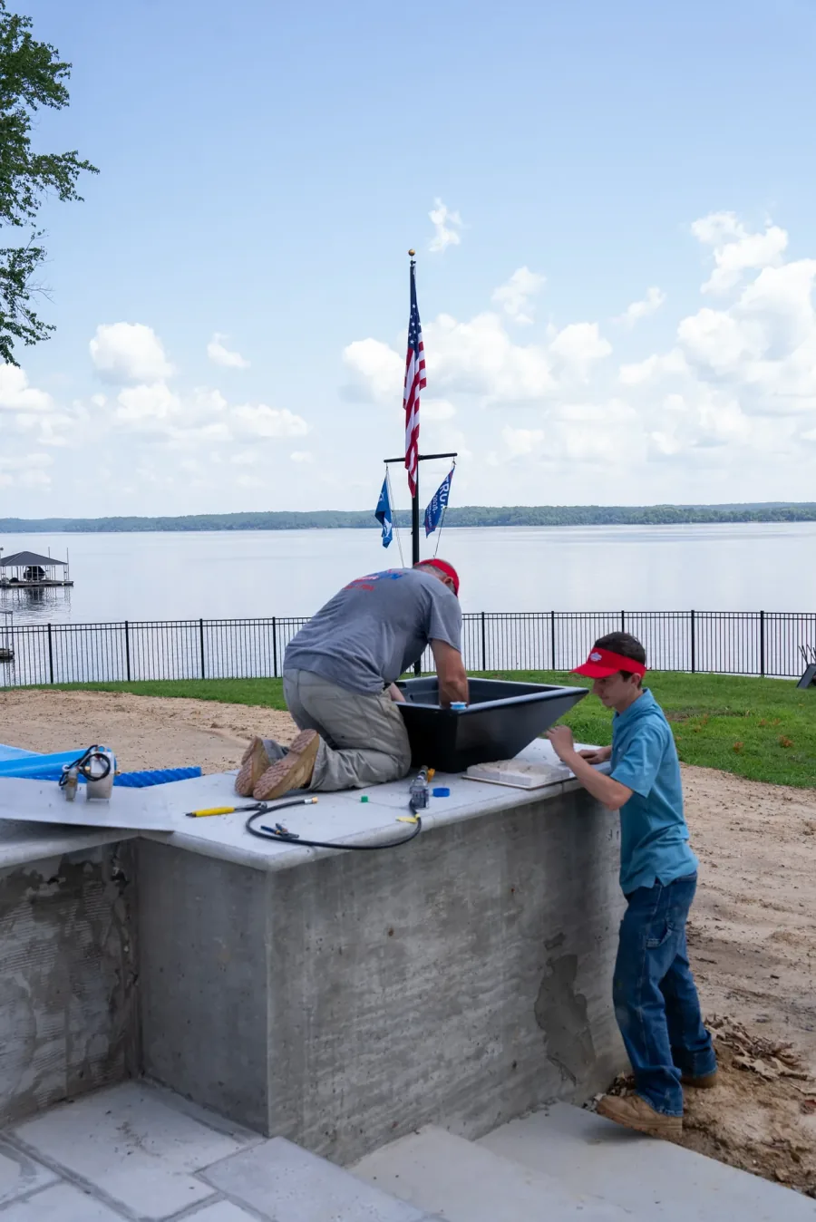 Two Stinson techs at an outdoor kitchen island under construction beside a lake